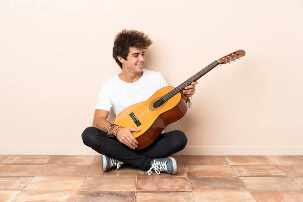 Jovem Caucasiano Com Uma Guitarra Sentada Chão Com Expressão Feliz — Fotografia de Stock