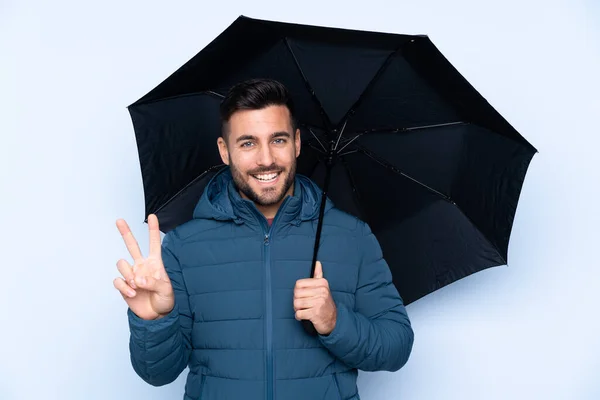 Muž Drží Deštník Nad Izolovaným Pozadím Usmívá Ukazuje Znamení Vítězství — Stock fotografie