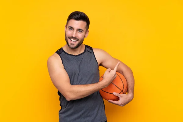 Hombre Sobre Fondo Amarillo Aislado Jugando Baloncesto Apuntando Hacia Lateral —  Fotos de Stock