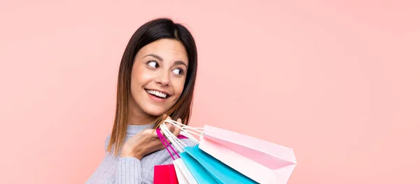 Kvinna Över Isolerade Rosa Bakgrund Håller Shoppingväskor Och Ser Tillbaka — Stockfoto