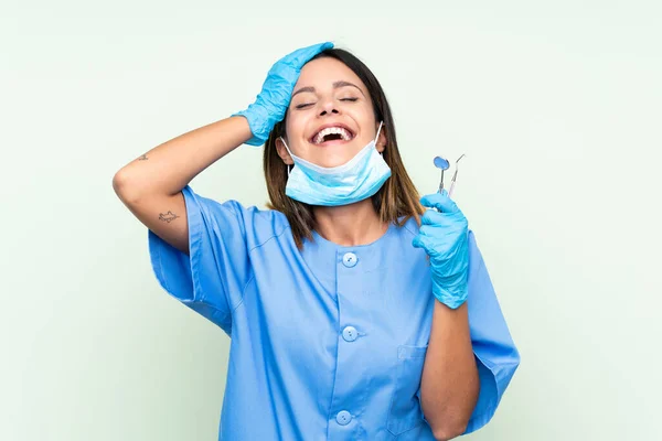 女牙医拿着工具在孤立的绿色背景下大笑 — 图库照片