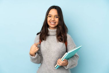 Okula giden genç melez kadın mavi arka planda yalnız gururlu ve kendini beğenmiş.