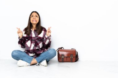 Genç bir bayan öğrenci yerde oturuyor ve şans diliyor.