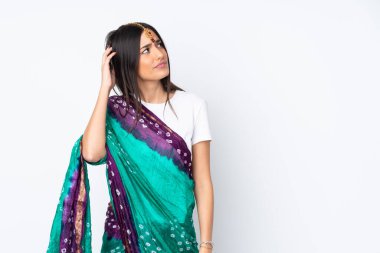 Beyaz arka planda izole edilmiş genç bir Hintli kadının şüpheleri var ve kafası karışmış bir yüz ifadesi var.