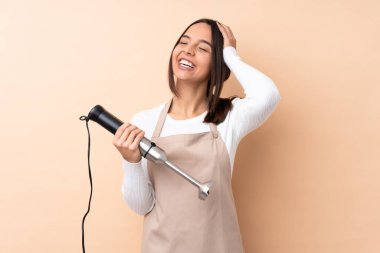 Genç esmer kız, el blendırını izole edilmiş arka planda sıkça gülümsüyor.