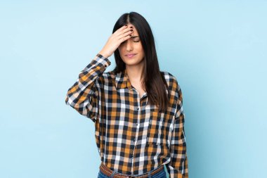 Kafkasyalı genç bir kadın mavi arka planda izole edilmiş, baş ağrısı var.