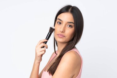 Beyaz arka planda izole edilmiş beyaz bir kadın elinde makyaj fırçası tutuyor.