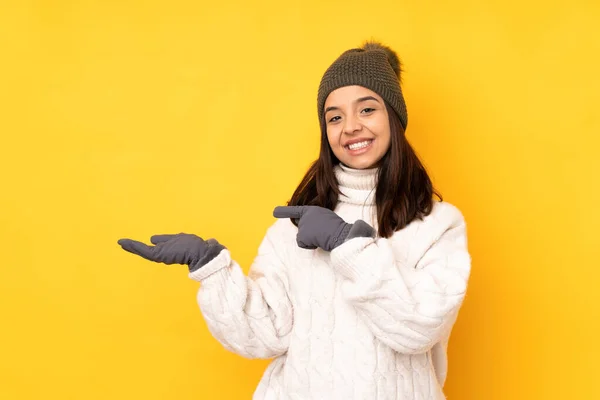 Ung Kvinna Med Vinter Hatt Över Isolerad Gul Bakgrund Håller — Stockfoto