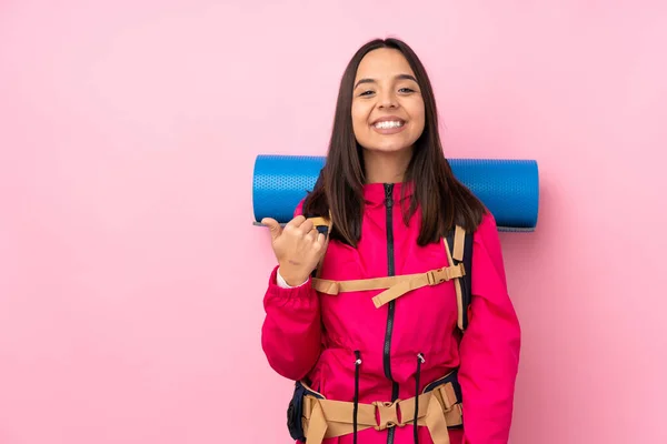 若いです登山の女の子とともに大きなバックパック上の隔離されたピンクの背景製品を提示する側を指して — ストック写真