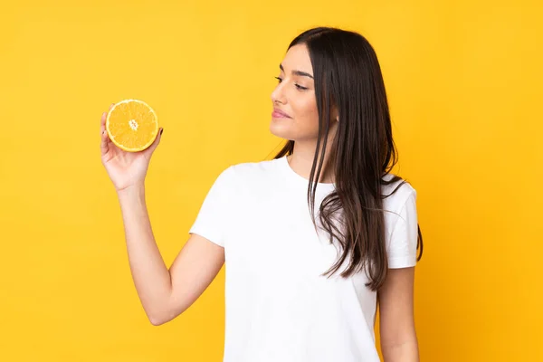 Junge Kaukasische Frau Hält Eine Orange Über Einem Isolierten Gelben — Stockfoto