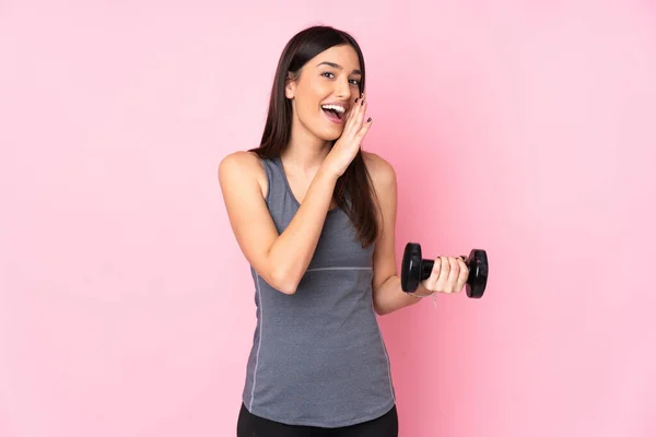 Giovane Donna Rendendo Sollevamento Pesi Isolato Sfondo Rosa Sussurrando Qualcosa — Foto Stock