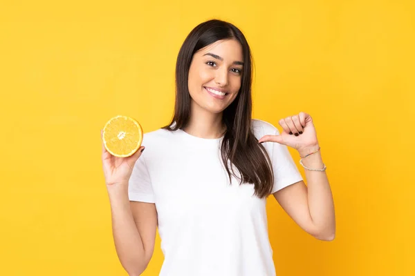 Ung Kaukasiska Kvinna Som Håller Orange Isolerad Gul Bakgrund Stolt — Stockfoto