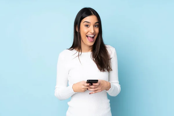 Mavi arka planda izole genç beyaz kadın şaşırdı ve bir mesaj gönderiyor.