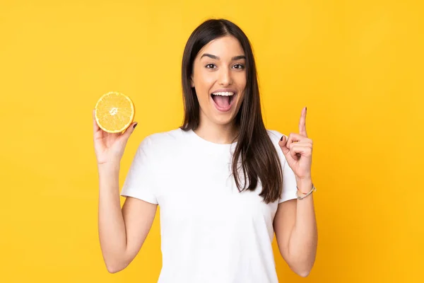 Ung Kaukasisk Kvinna Som Håller Orange Isolerad Gul Bakgrund Pekar — Stockfoto