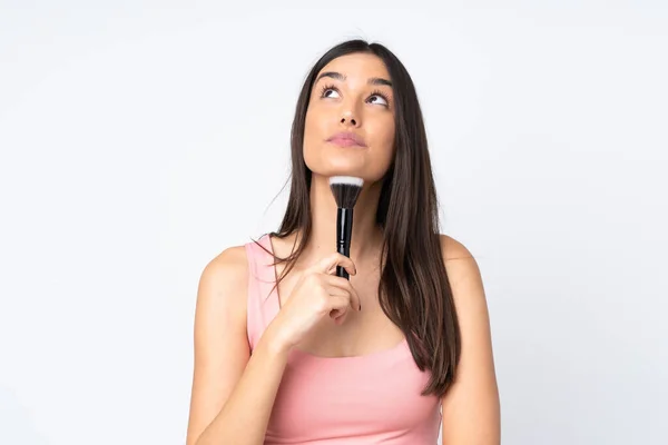 Mulher Branca Jovem Isolado Fundo Branco Segurando Escova Maquiagem Pensando — Fotografia de Stock