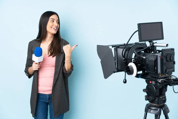 Mulher Repórter Segurando Microfone Reportando Notícias Isoladas Fundo Azul Apontando — Fotografia de Stock