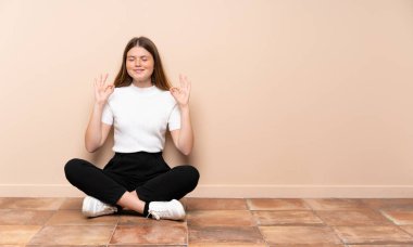 Zen pozuyla yerde oturan Ukraynalı genç kız.