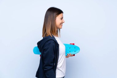 İzole edilmiş mavi arka planı olan genç bir kadın, yan pozisyonda kayıyor.