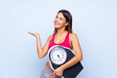 Tartı makinesi ile izole edilmiş mavi arkaplan üzerinde tartı makinesi olan kız