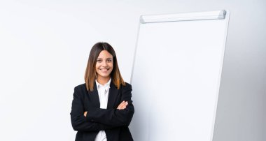 Beyaz tahtada sunum yapan genç bir kadın çok fazla gülümsüyor.