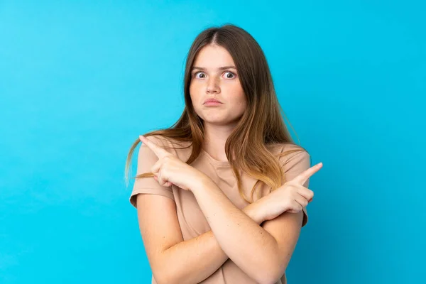 Oekraïense Tiener Meisje Geïsoleerde Blauwe Achtergrond Wijzend Naar Lateralen Met — Stockfoto