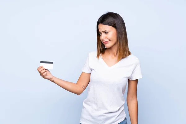 Ung Kvinna Över Isolerad Blå Bakgrund Innehar Ett Kreditkort — Stockfoto