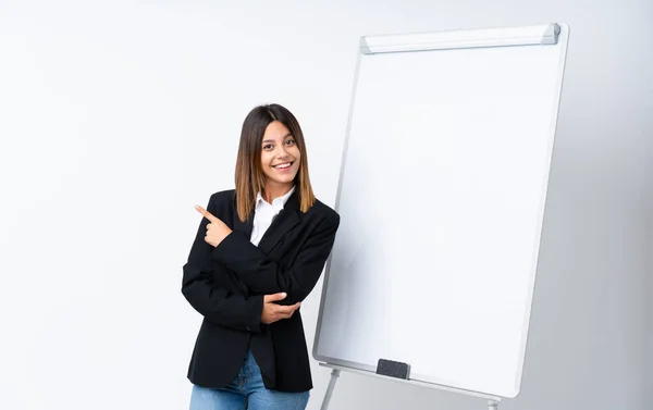 Young woman giving a presentation on white board pointing to the side to present a product