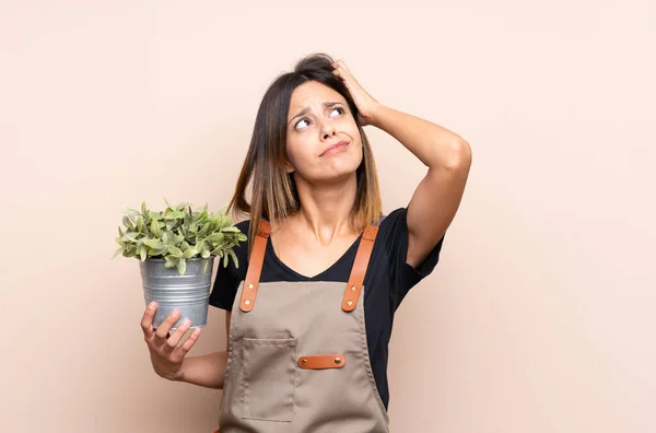 Jonge Vrouw Met Een Plant Die Twijfelt Met Verwarrende Gezichtsuitdrukking — Stockfoto