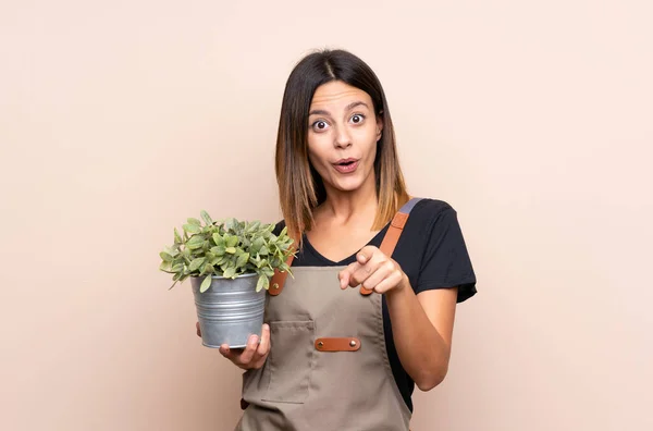 Jonge Vrouw Houdt Een Plant Verrast Wijst Naar Voren — Stockfoto