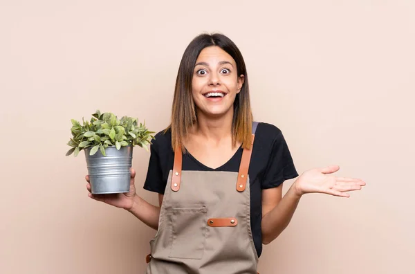 Giovane Donna Che Tiene Una Pianta Con Espressione Facciale Scioccata — Foto Stock