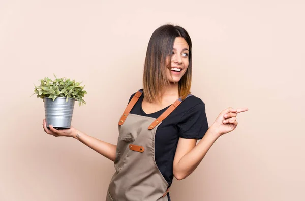 Mujer Joven Sosteniendo Una Planta Apuntando Hacia Lado Para Presentar — Foto de Stock