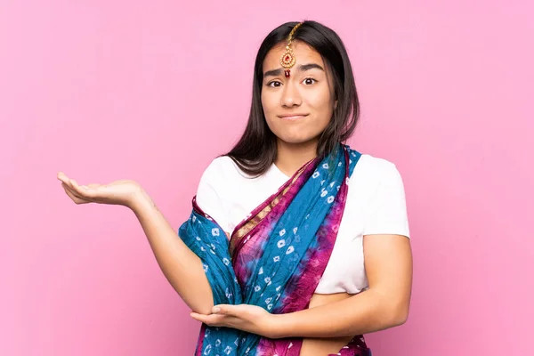 Young Indian woman with sari over isolated background unhappy for not understand something