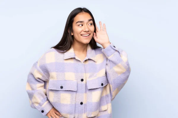 Jovem Indiana Isolada Fundo Azul Ouvindo Algo Colocando Mão Orelha — Fotografia de Stock