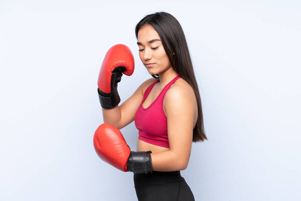 Young Indian sport woman isolated on blue background with boxing gloves