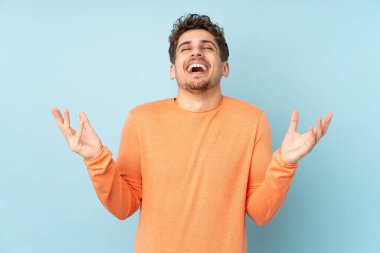 Mavi arka planda izole edilmiş beyaz bir adam çok fazla gülümsüyor.