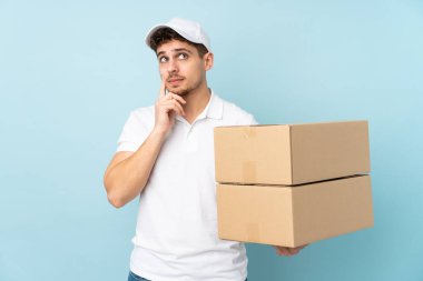 Teslimat yapan beyaz adam mavi arka planda izole edilmiş bir fikir düşünüyor.