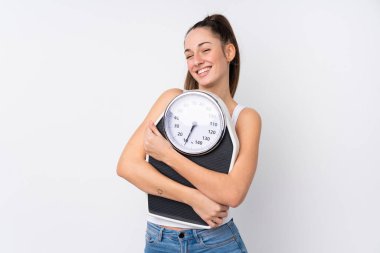 Genç esmer kadın, izole edilmiş beyaz arka planda tartı makinesiyle.