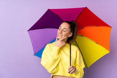 Mor duvarın üzerinde şemsiyesini tutan genç esmer kadın bir fikir üretiyor ve ona bakıyor.