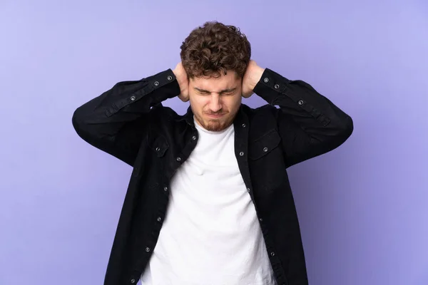 Caucasian man isolated on purple background frustrated and covering ears