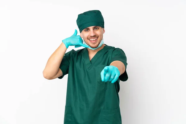 身穿绿色制服的外科医生隔离在孤立的白色背景下 做出电话手势并指向前方 — 图库照片