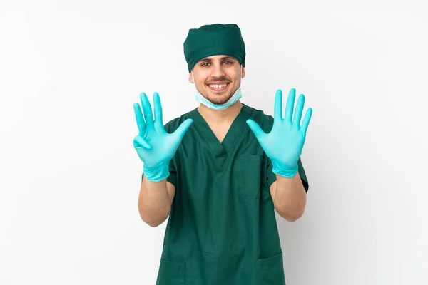身穿绿色制服的外科医生被隔离在孤立的白色背景上 用手指数着9 — 图库照片