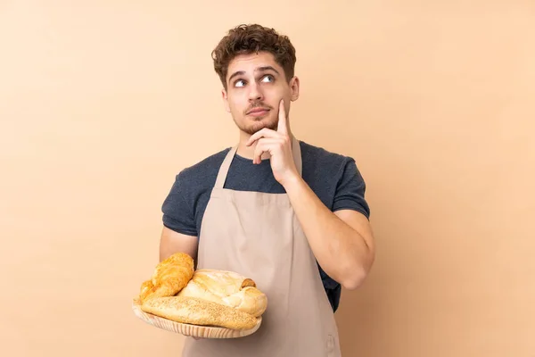 Männlicher Bäcker Hält Einen Tisch Mit Mehreren Broten Auf Beigem — Stockfoto