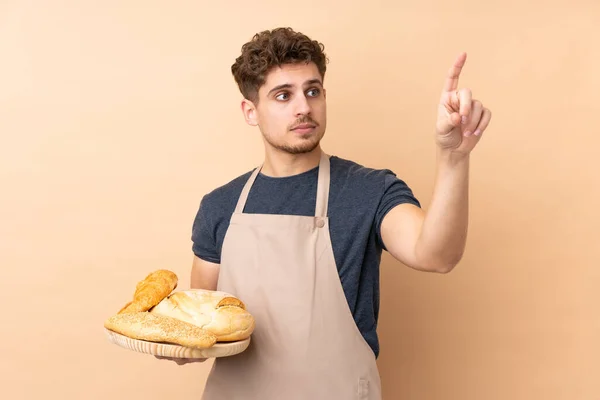 Männlicher Bäcker Hält Einen Tisch Mit Mehreren Broten Auf Beigem — Stockfoto