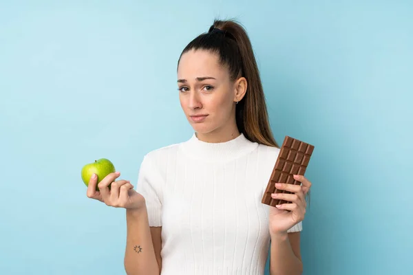 Young Brunette Woman Isolated Blue Background Taking Chocolate Tablet One — 스톡 사진