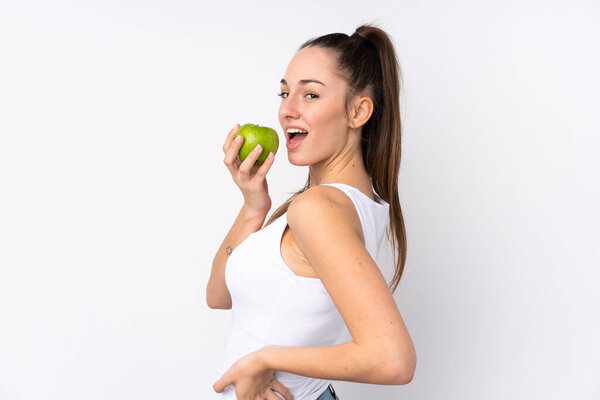 Молодая брюнетка на изолированном белом фоне ест яблоко
