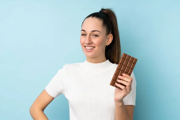 Mladá Brunetka Žena Přes Izolované Modré Pozadí Čokoládovou Tabletu Šťastný — Stock fotografie