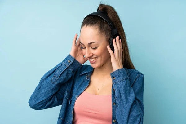 Joven Morena Sobre Fondo Azul Aislado Escuchando Música —  Fotos de Stock