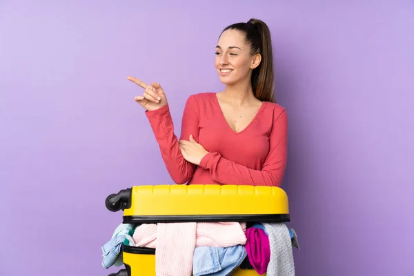 Traveler Woman Suitcase Full Clothes Isolated Purple Background Pointing Finger — Stock Photo, Image