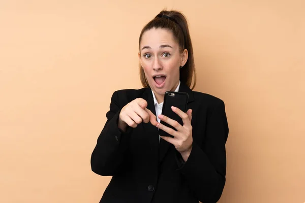 Young Business Woman Using Mobile Phone Isolated Background Surprised Pointing — Stock Photo, Image