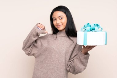 Genç Asyalı kız elinde büyük bir pasta tutuyor bej arka planda soyutlanmış gururlu ve kendini beğenmiş.